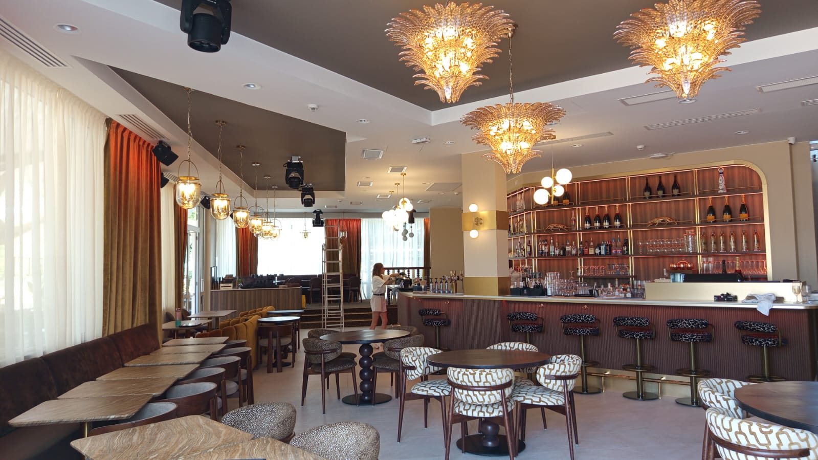 Bar de réception : lustres en verre ambré, plafond taupe, bar en bois cannelé et banquettes de velours