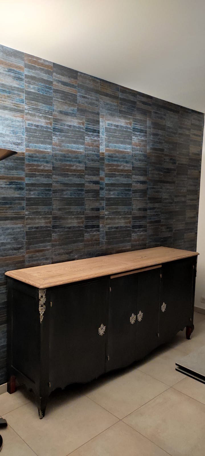 Salon habillé d’un revêtement mural intissé bleu profond, devant un buffet ancien patiné de noir