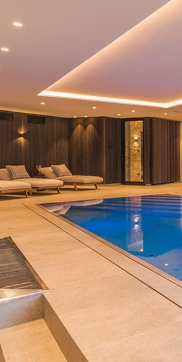Espace SPA d’une résidence privée : piscine intérieure bordée de boiseries sombres et d’un éclairage tamisé, réalisé par Pavia Décor